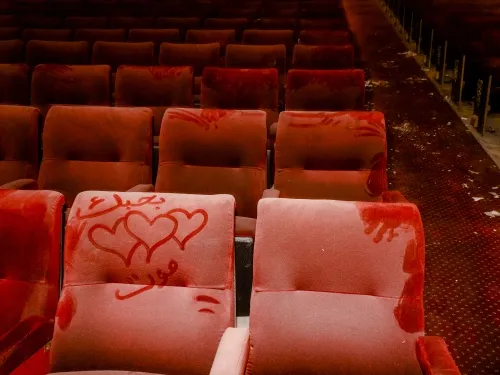 A pair of hearts drawn in dust accumulated on a movie theater seat.